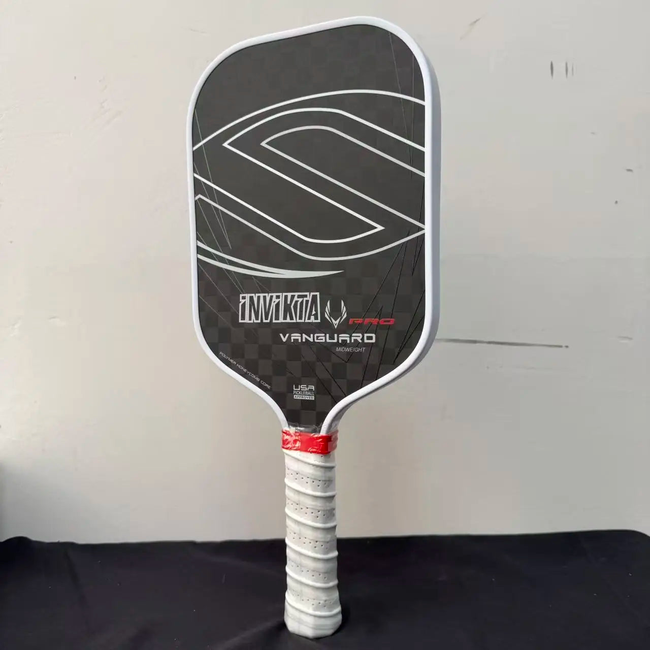 12K pickleball paddle with a 16mm polymer honeycomb core, designed for enhanced spin and power; black with white accents, includ